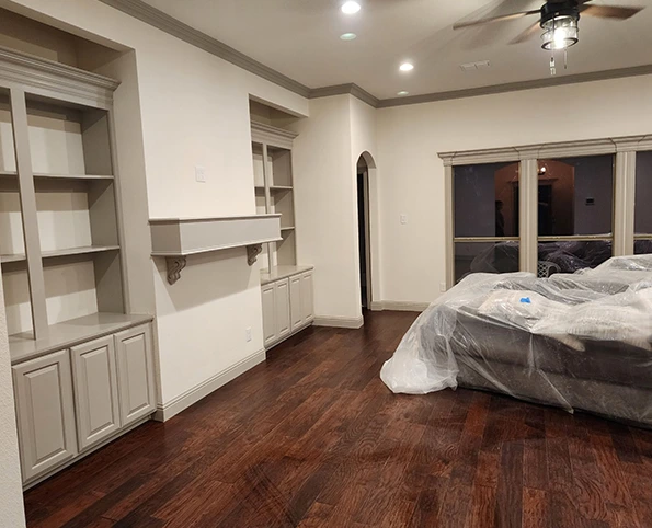 Living room with built-in shelves, wood floors. Contact us for a reliable wall patching service!