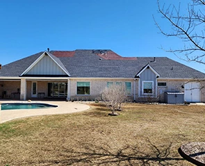 Backyard view of a house with exterior updates, pool, and brown lawn.