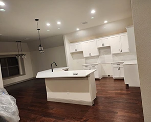 Newly installed dark hardwood flooring in a modern kitchen with white cabinets and island.